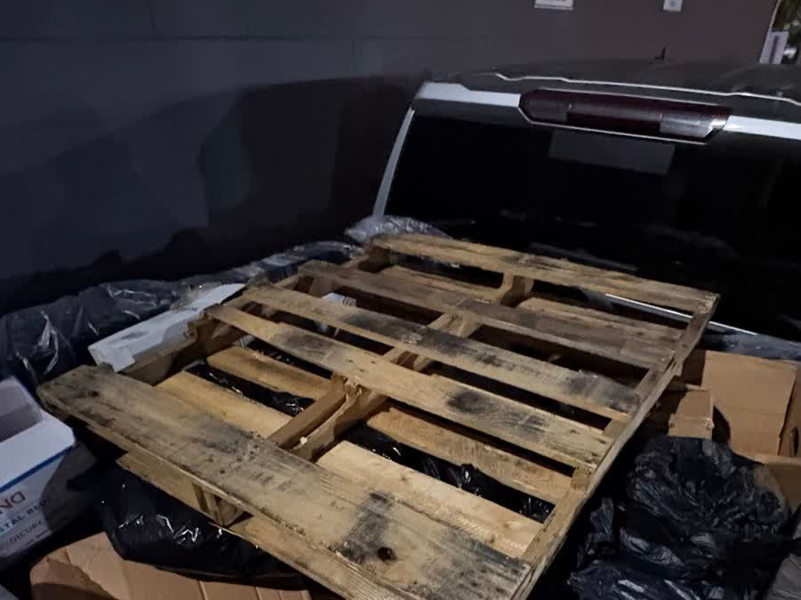 Truck bed loaded with bagged trash and a pallet